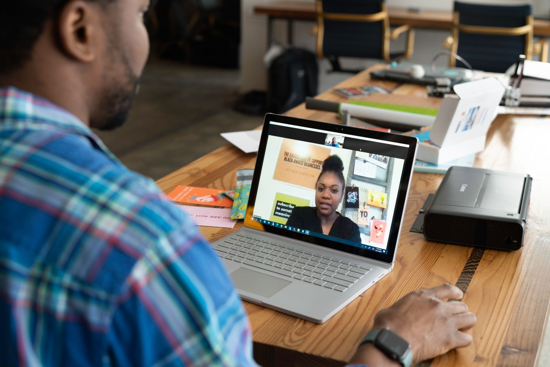 Remote employees communicating through computers during a collaborative video meeting from separate workspaces.